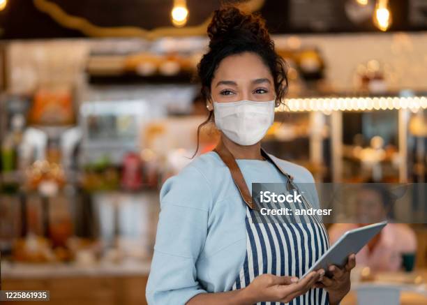 Beautiful Waitress Working At A Restaurant Wearing A Facemask Stock Photo - Download Image Now