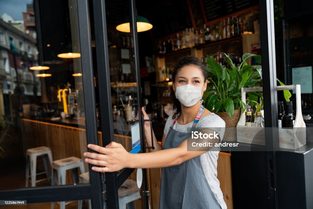 얼굴 마스크를 쓰고 카페에서 문을 여는 행복한 비즈니스 오너 - 로열티 프리 보호 마스크 스톡 사진