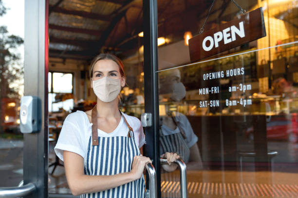 フェイスマスクを着用したカフェでドアを開ける幸せなビジネスオーナー - シドニー 写真 ストックフォトと画像