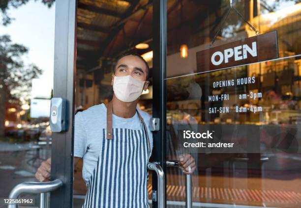 Business Owner Opening The Door At A Cafe Wearing A Facemask Stock Photo - Download Image Now