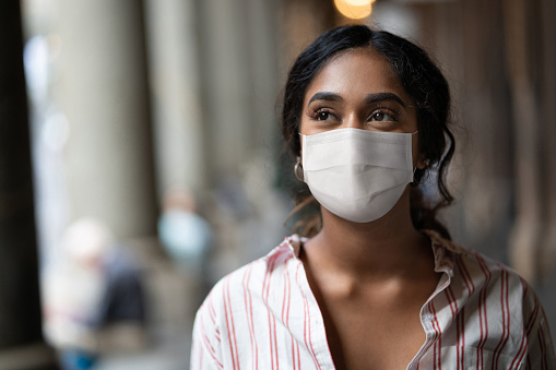 Mujer de raza mixta pensada en la calle con una máscara facial photo