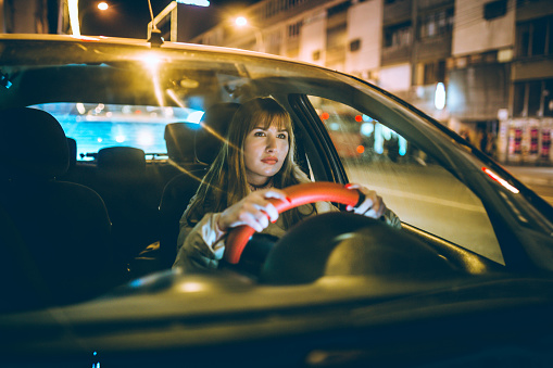 Young caucasian woman driving car at night
