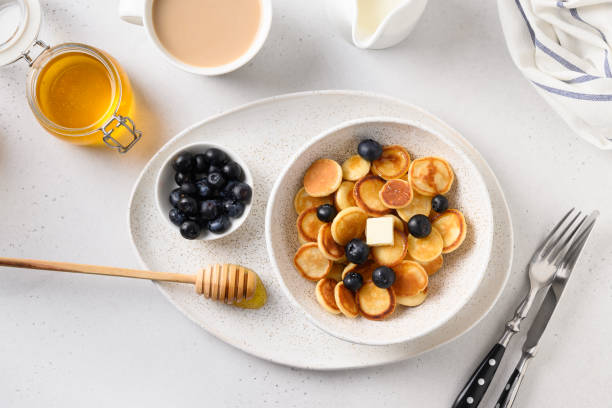 istock Tiny cereal pancakes with blueberry and honey on white background. View from above. 1225864236