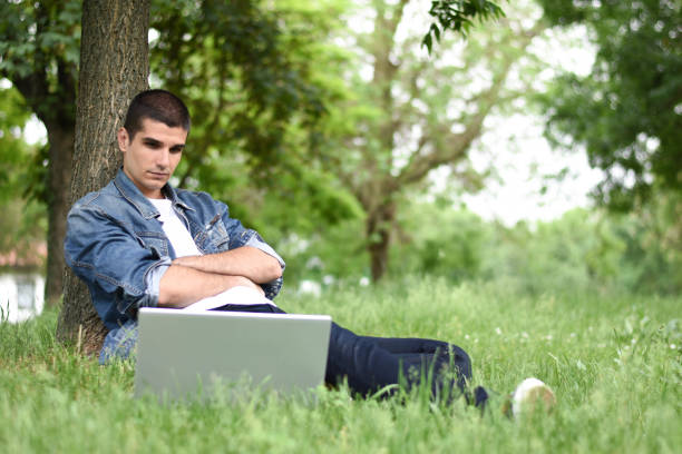 istock Young man working on laptop in the park 1225866057