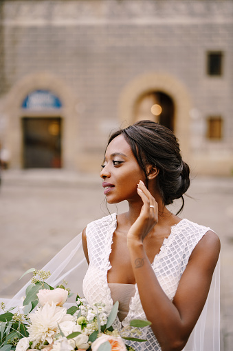 African-American bride in white dress and long veil. With a lush bouquet of the bride in her hands. Wedding in Florence, Italy.