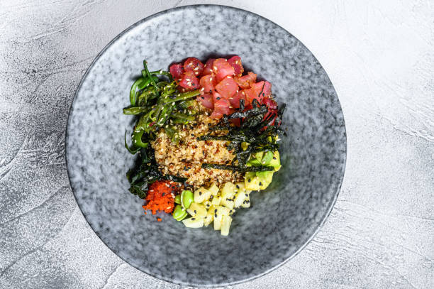 Poke bowl with raw tuna fish and vegetables. Hawaiian dish. Healthy eating concept. Gray background. Top view