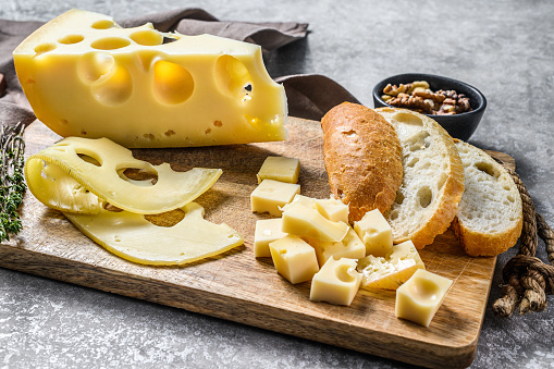 Maasdam cheese with walnut and thyme. Gray background. Top view.