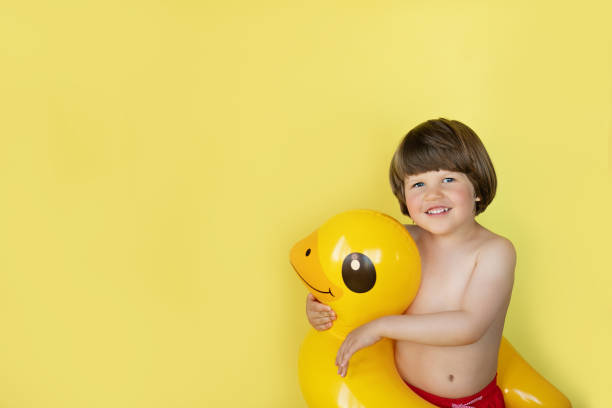 istock Little boy smiling and hugging yellow duck inflatable pool float with copy space 1225870741
