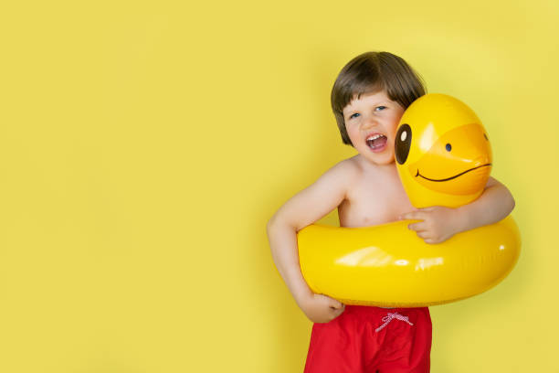 istock Boy laughing wearing yellow duck inflatable pool float on the background 1225870773