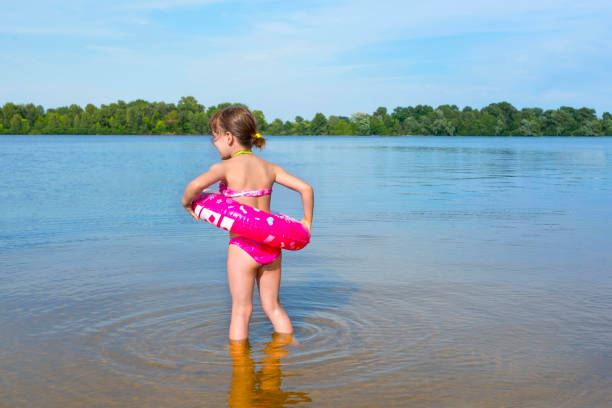 istock Child with a rubber ring on the beach on a sunny day. The view from the back. 1225870912