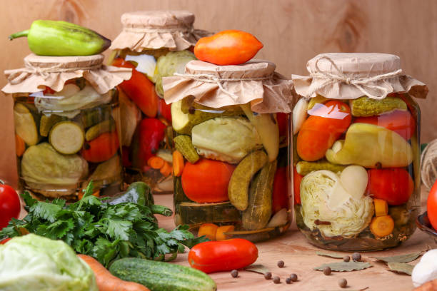 istock Assorted pickled vegetables in jars: cucumbers, tomatoes, cabbage, zucchini and peppers with garlic, dill and bay leaves in jars on a wooden background, rustic style 1225873386