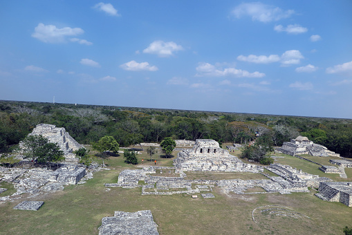Mayapan, Yucatan, Mexico - Jan. 28, 2020: Visitors walk through the grounds of the Mayan ruins at Mayapan, seen from the top of the Temple of Kukulcan pyramid, the tallest structure at the site located 35 miles southeast of Merida.  Mayapan was the Mayan capital of the Yucatan peninsula from approximately 1200 A.D. to 1400 A.D.