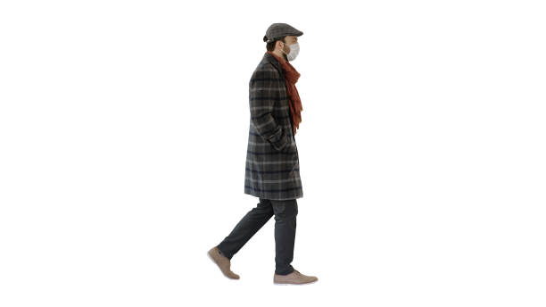 istock Gentleman wearing a protective face mask walking on white background 1225877902