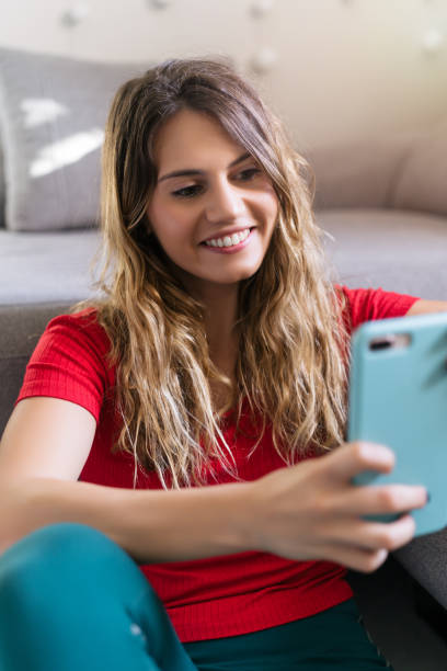 istock happy woman smiling using smartphone at home 1225878191