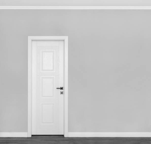 istock Beautiful wooden white door on empty grey wall with copy space for your text. 1225880392
