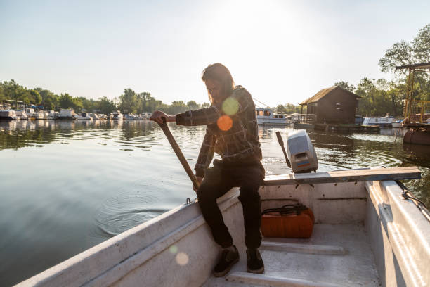 istock Man in old white boat is rowing in sunrise 1225883142
