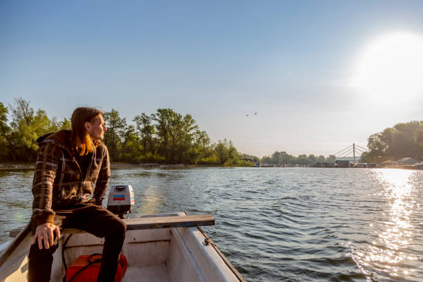istock Sad man is riding a boat over river in sunset 1225883313