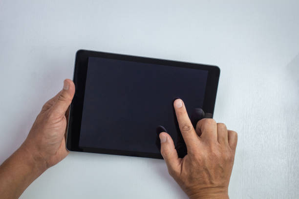 istock Male hands working on a tablet isolated on white textured wooden background 1225886090
