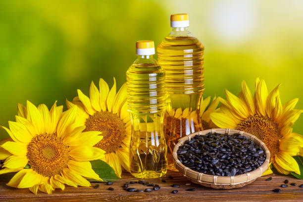 ländliches stillleben - sonnenblumenöl in flaschen mit sonnenblumenblüten - sunflower seed oil stock-fotos und bilder