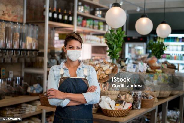 Geschäftsinhaber Arbeitet In Einem Lebensmittelgeschäft Mit Einer Gesichtsmaske Stockfoto und mehr Bilder von Speisen