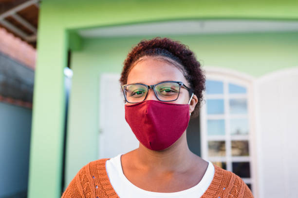 Woman in front of home wearing face mask Smile behind the mask during the Covid-19 pandemic. garden accessories stock pictures, royalty-free photos & images