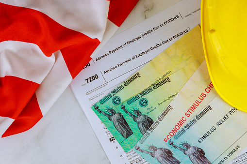 American flag on Stimulus financial relief check to the Passport of USA in yellow hard hat