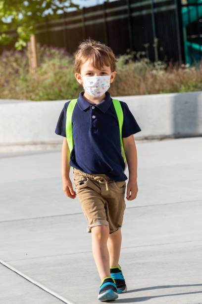 istock Little schoolboy wearing a protective mask and a backpack 1225905552