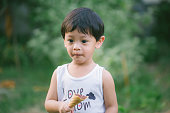 Asia boy he mouth aftertaste from eating chocolate ice cream  or chocolate dessert. A sweet-toothed child eat chocolate. Kid with dirty face eating ice cream. Cute toddler boy eating icecream.