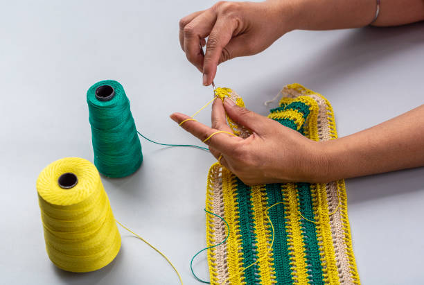 Woman crocheting pattern with crochet hook close-up.
