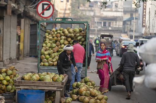 Delhi, India - January 30th, 2020: Unidentified vendor unloads coconuts for sale on street of Old Delhi, India. Street markets still play a significant role in sourcing quality of food products in India.