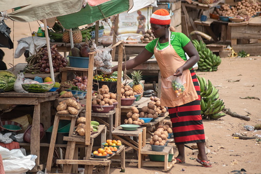 Mubende, Uganda - January 25th, 2020: Unidentified woman sells potatoes at a road market in Mubende, Uganda. Street markets play a significant role for local farmers.