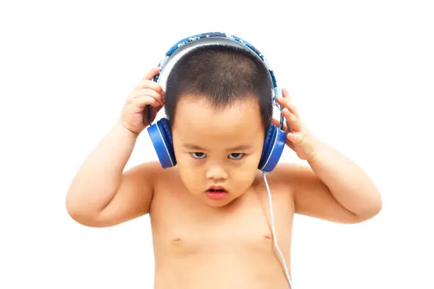 The little boy listens to rock music from the headphones. And with a serious expression.