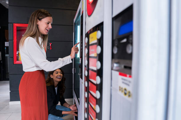 las compañeras de trabajo están en el trabajo usando la máquina expendedora de la oficina de coworking - vending machine fotos fotografías e imágenes de stock