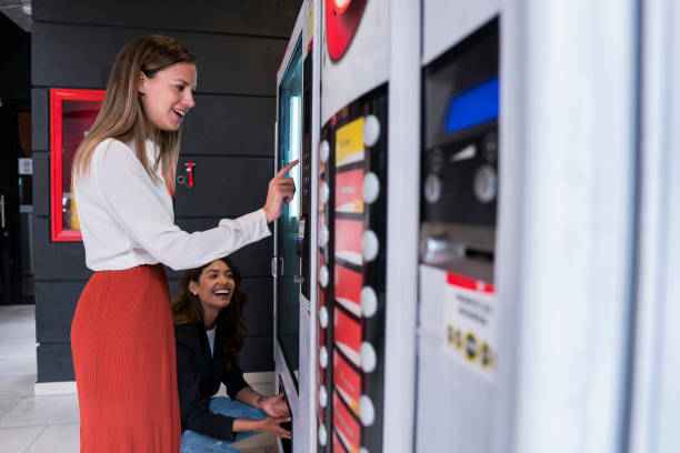 여성 동료는 공동 작업 사무실 자동 판매기를 사용하여 직장에서 휴식 - vending machine 뉴스 사진 이미지
