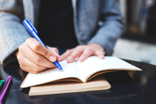 istock a woman writing on a blank notebook with colored pens on the table 1225920311