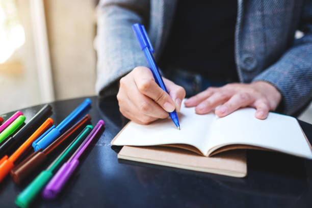 istock a woman writing on a blank notebook with colored pens on the table 1225920365