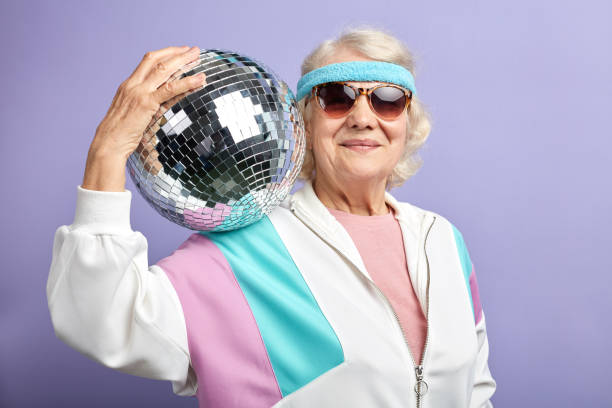 istock Positive elderly lady holds sparkling disco ball, dressed smiling at camera. 1225921546
