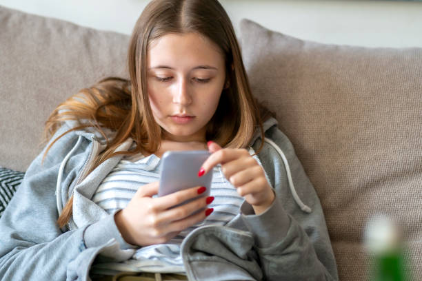 istock Young woman sitting on the sofa using her smartphone 1225925054