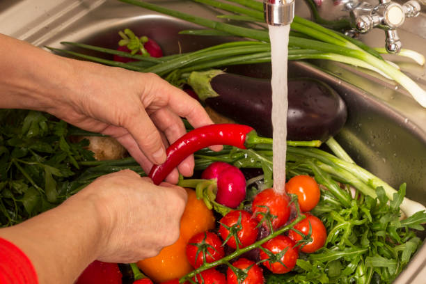 istock Hands wash vegetables in sink. Water pours from tap. 1225925159