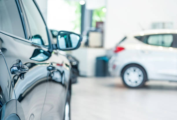 New cars at dealer showroom New cars at dealer showroom. Blurred background. Fokus is on the handle from the left car empty dealership interior stock pictures, royalty-free photos & images