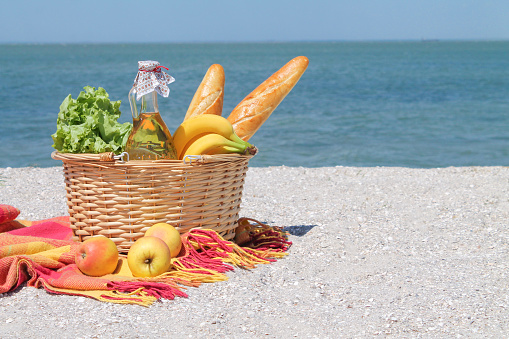 Picnic basket with food and wine on the beautiful beach. Outdoor leisure concept