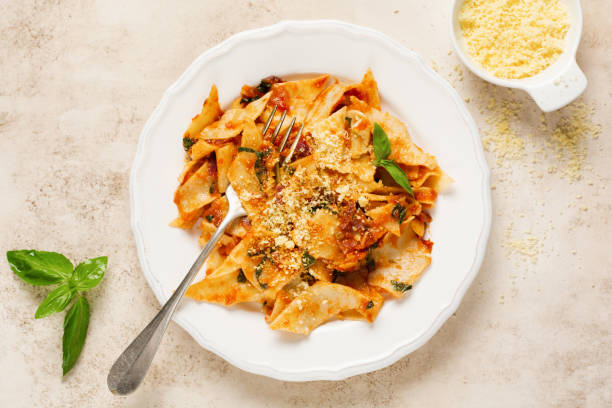 istock Pasta Maltagliati with classic tomato sauce, parmesan and basil on a rustic concrete light table background. Traditional Italian dish serving. Top view. 1225933592