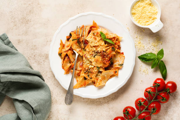 istock Pasta Maltagliati with classic tomato sauce, parmesan and basil on a rustic concrete light table background. Traditional Italian dish serving. Top view. 1225934885