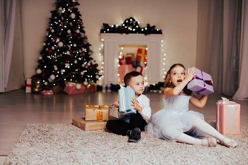 boy and girl family opens Christmas gift new year holiday lights Christmas tree