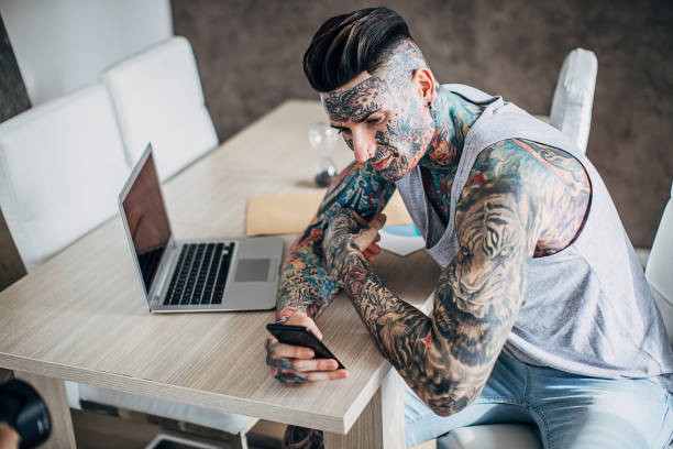 istock Man with whole body covered in tattoos using smart phone at home 1225938660