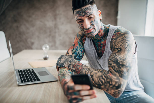 istock Man with whole body covered in tattoos using smart phone at home 1225938787