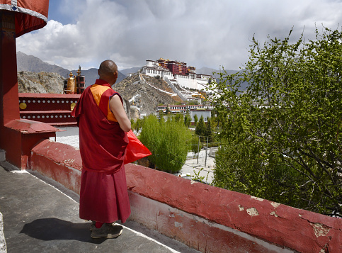 A Buddhist monk stands on  a terrace overlooking The Potala Palace in Lhasa at dawn set against Himalayan mountains. Tibet
The historic residence of the Dalai Lama of Tibet, constructed from 1645 - now a museum that dominates the skyline of Lhasa