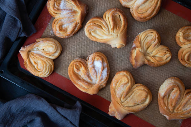 Homemade sugar buns on a baking sheet. Palmiers, elephant ear, puff pastry cookie Homemade sugar buns on a baking sheet. Palmiers, elephant ear, puff pastry cookie. plushka stock pictures, royalty-free photos & images