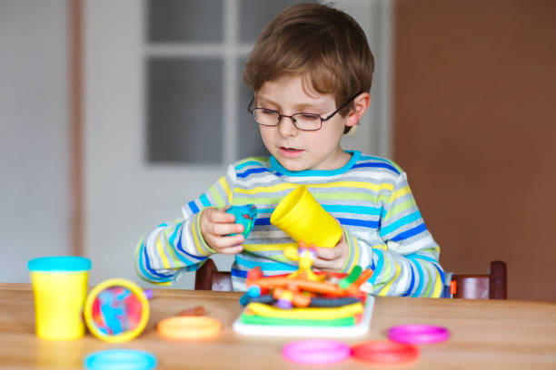 istock Smiling preschool kid boy having fun with dough, colorful modeling compound clay. Creative leisure with children. during corona virus quarantine staying at home. Shelter in place, lockdown concept, 1225951901
