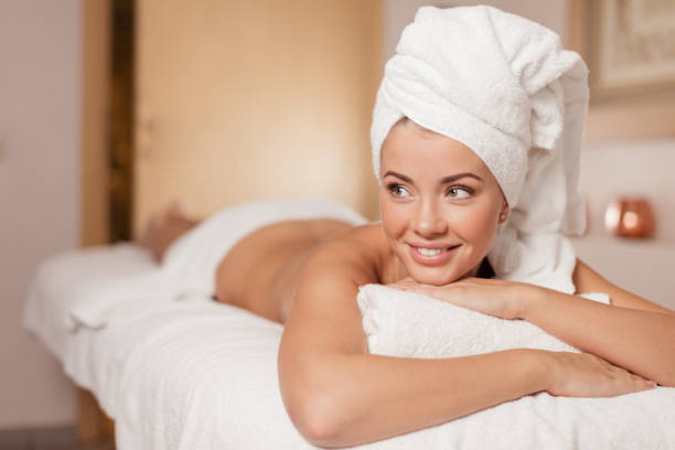 female massage therapist gently begins a forehead massage on a lying client of the salon.